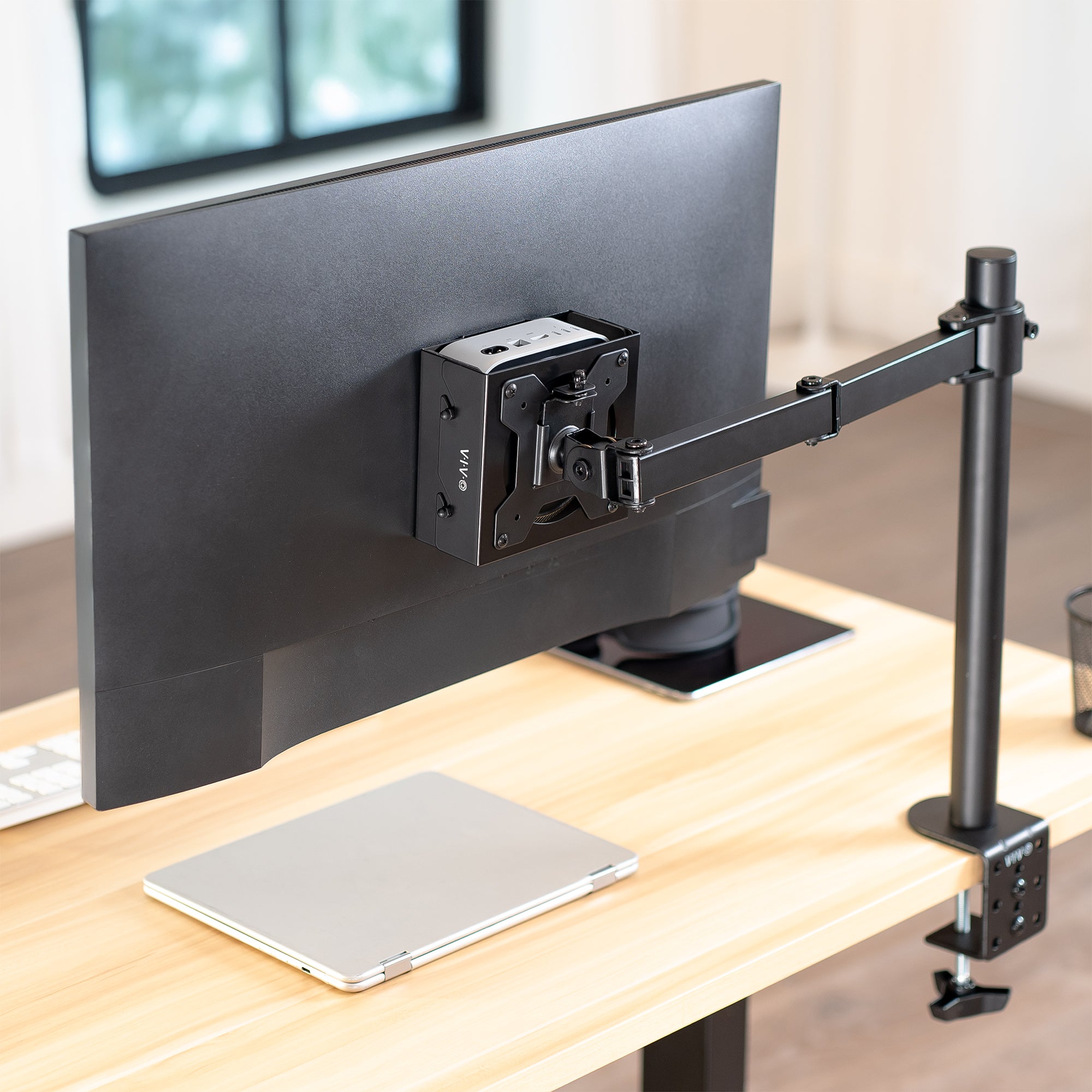 VESA / Clamp / Desk Mount Designed for Mac Mini 2024 mounted to monitor stand in an office setting.