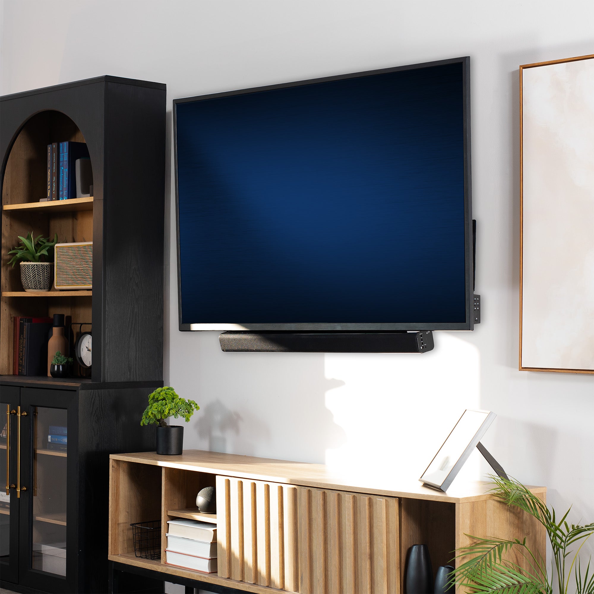 Modern living room with a flat-screen TV mounted on the wall with a Soundbar TV Mount, wooden entertainment console, and bookshelf.
