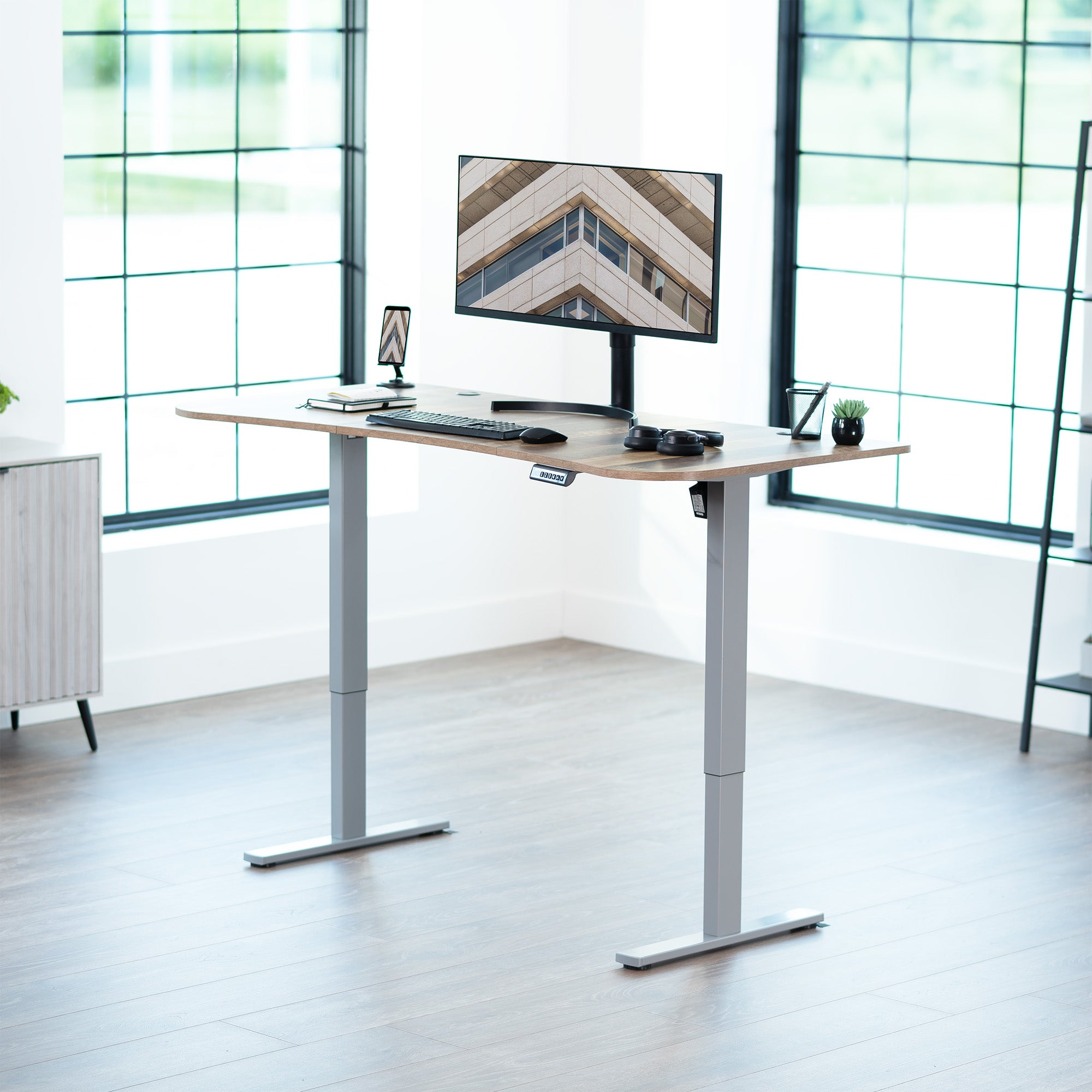 Reclaimed wood top grey frame, electric, sit to stand, height adjustable desk in office setting.