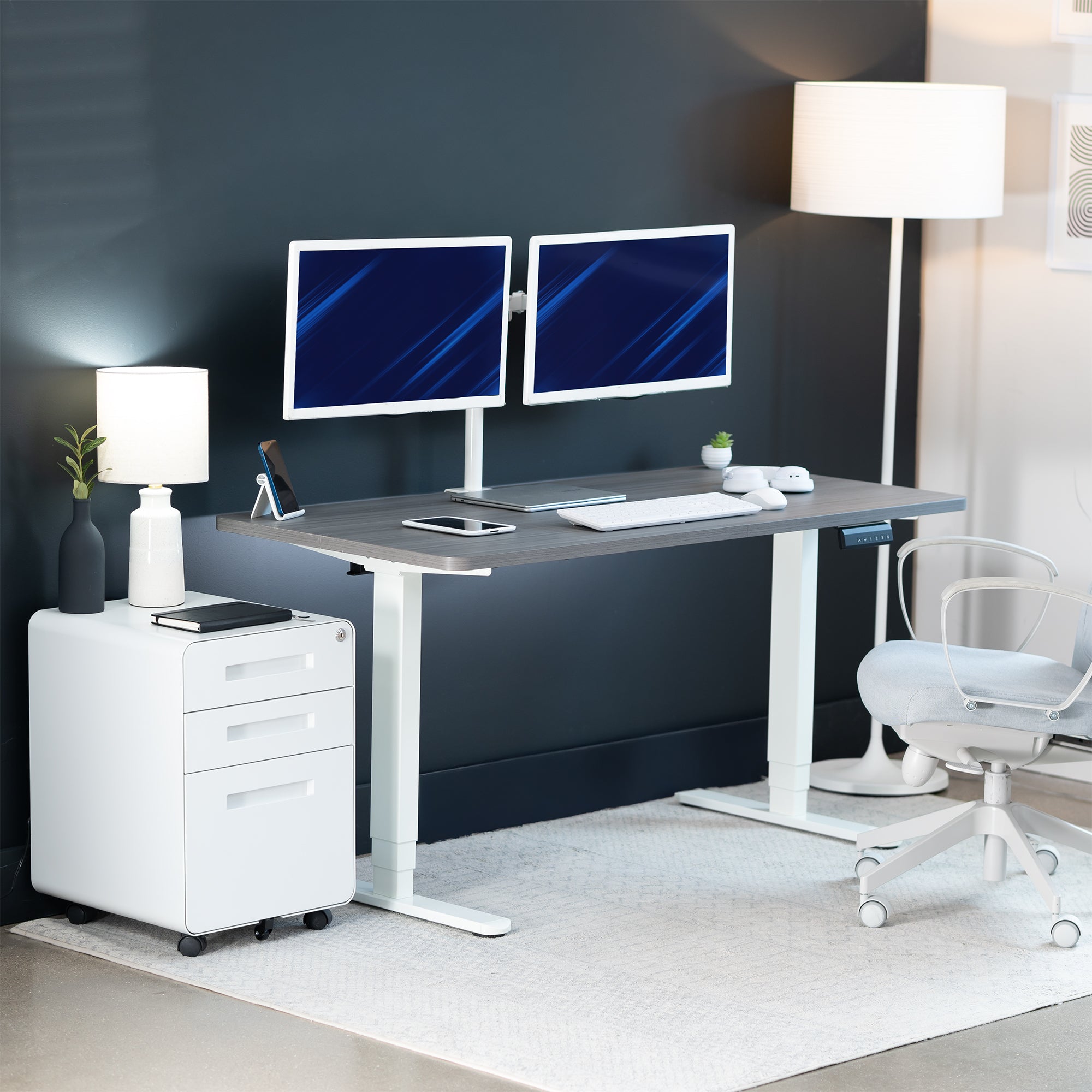 Modern office setup with a standing desk, computer monitors, and office chair.