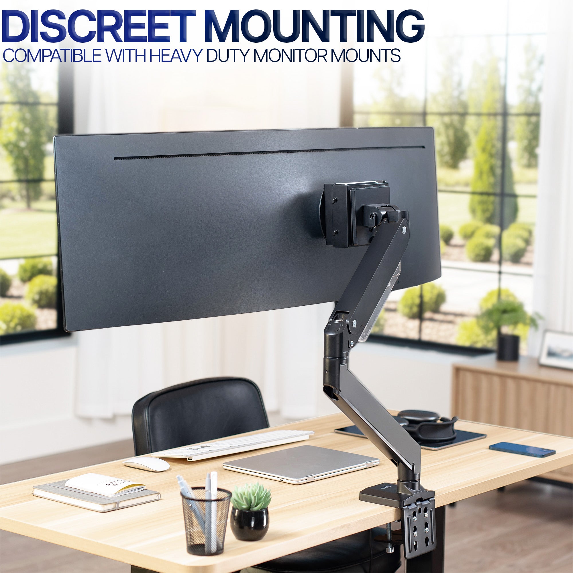 Monitor mount with Mac Mini mounted behind screen on a desk with a modern office background