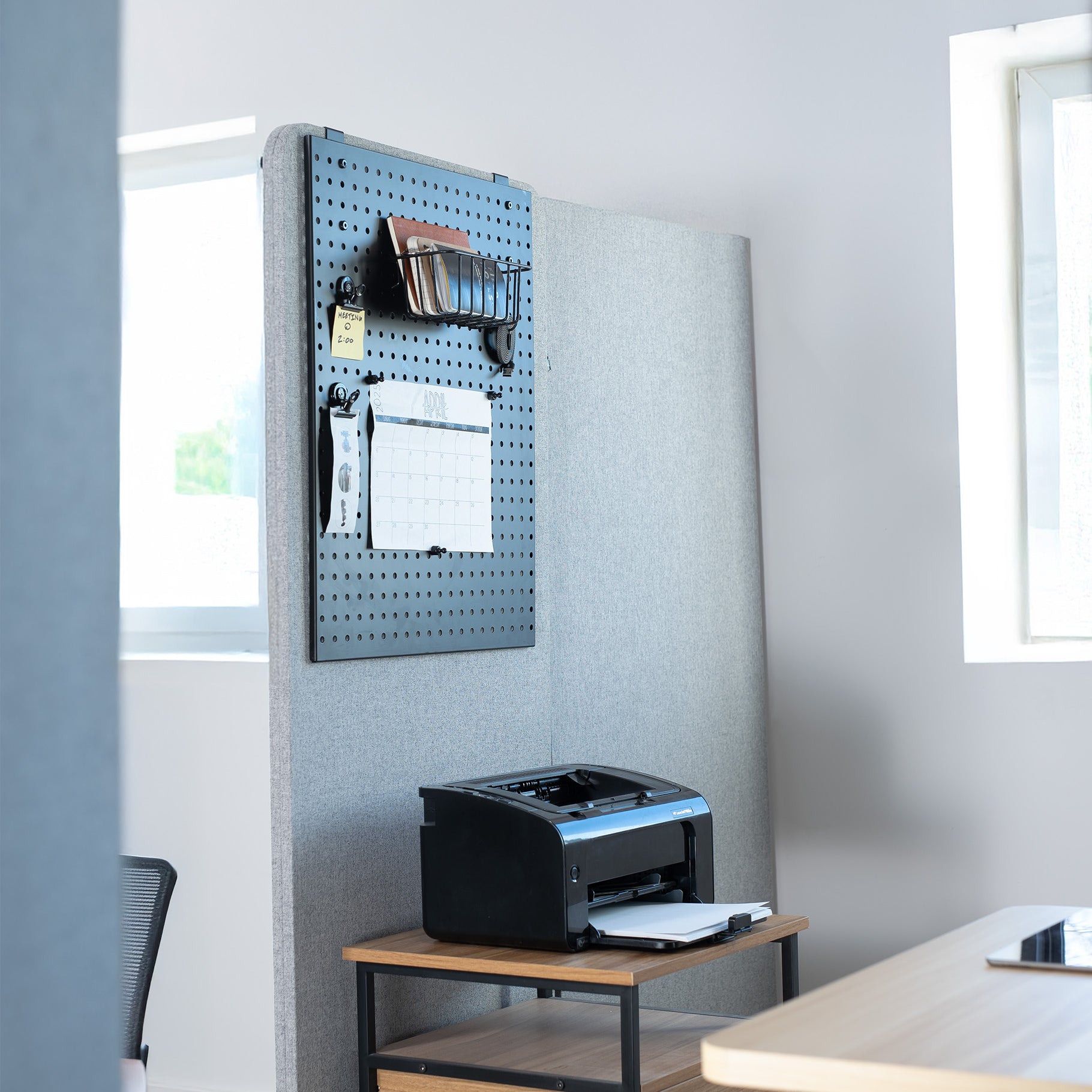 Printers on a wooden desk with a pegboard wall in an office setting