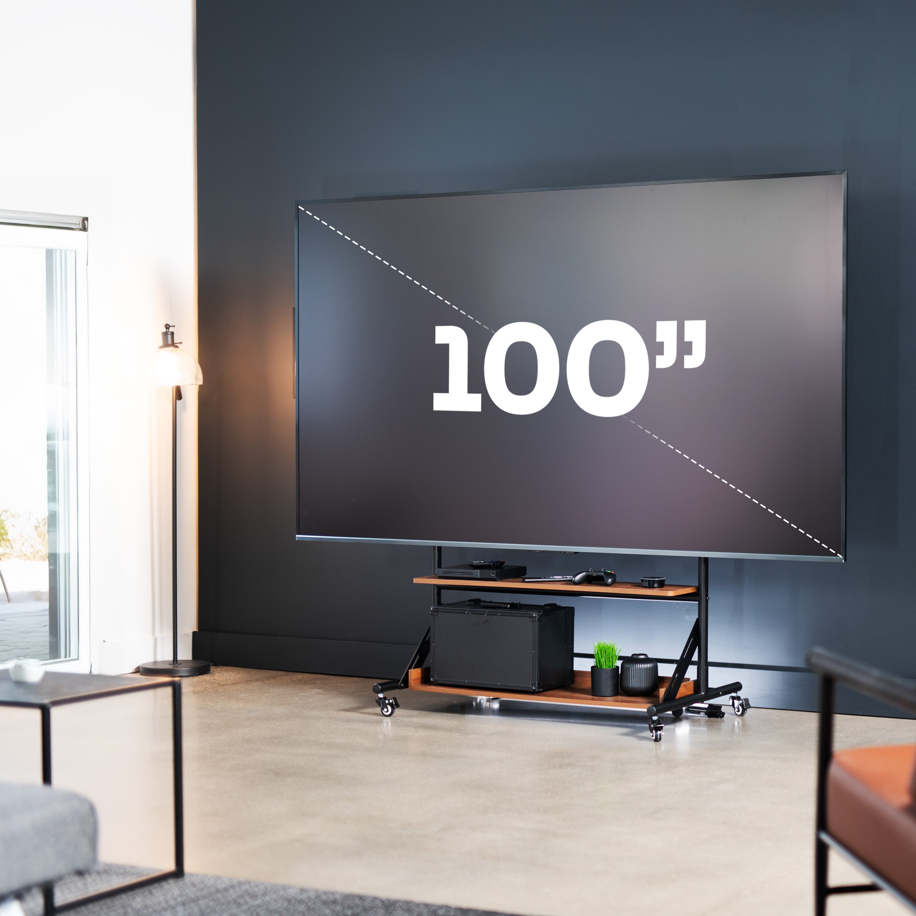 A heavy duty TV cart with dark wood shelves holding a large screen in a living room.