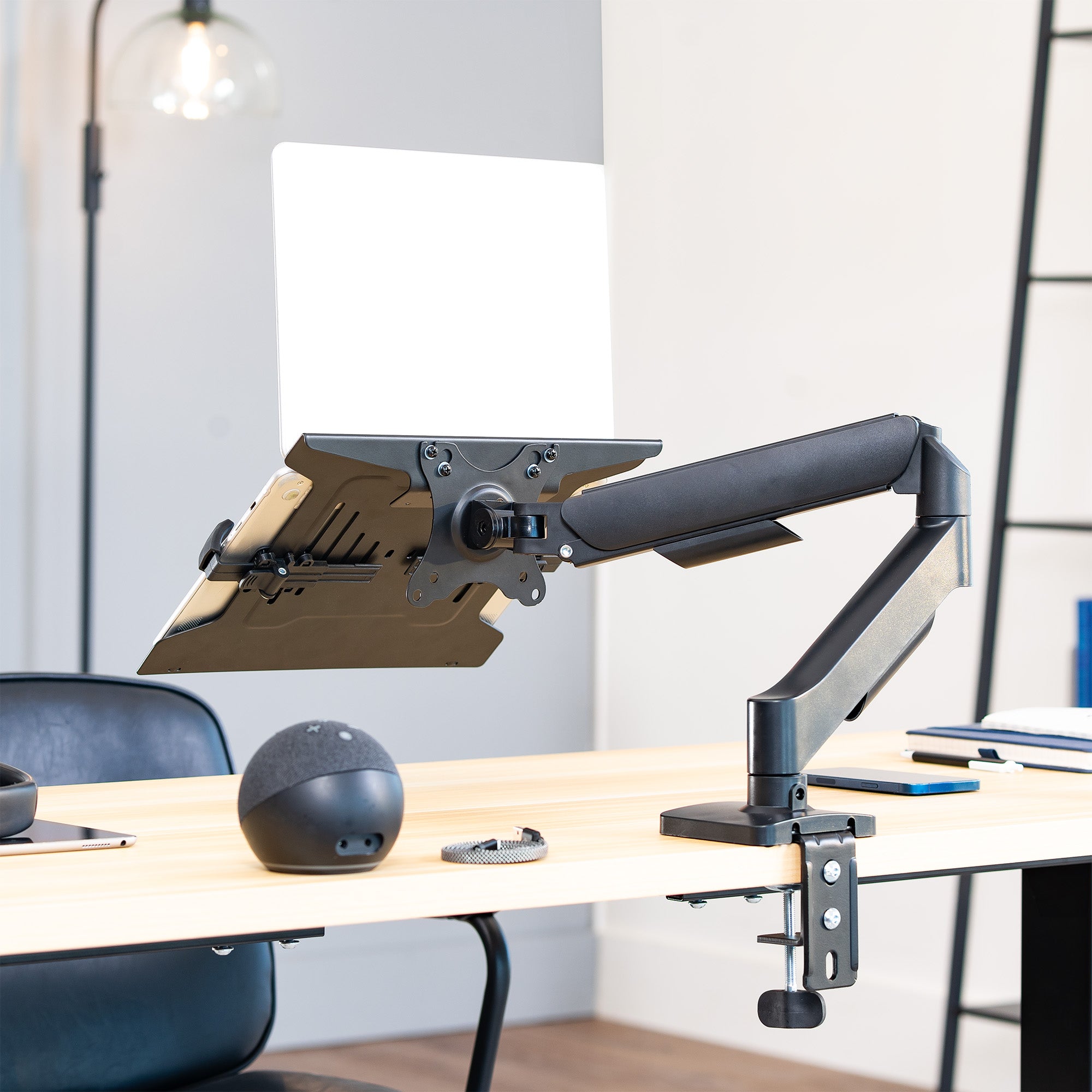 Adjustable laptop desk mount on a desk with desk accessories.