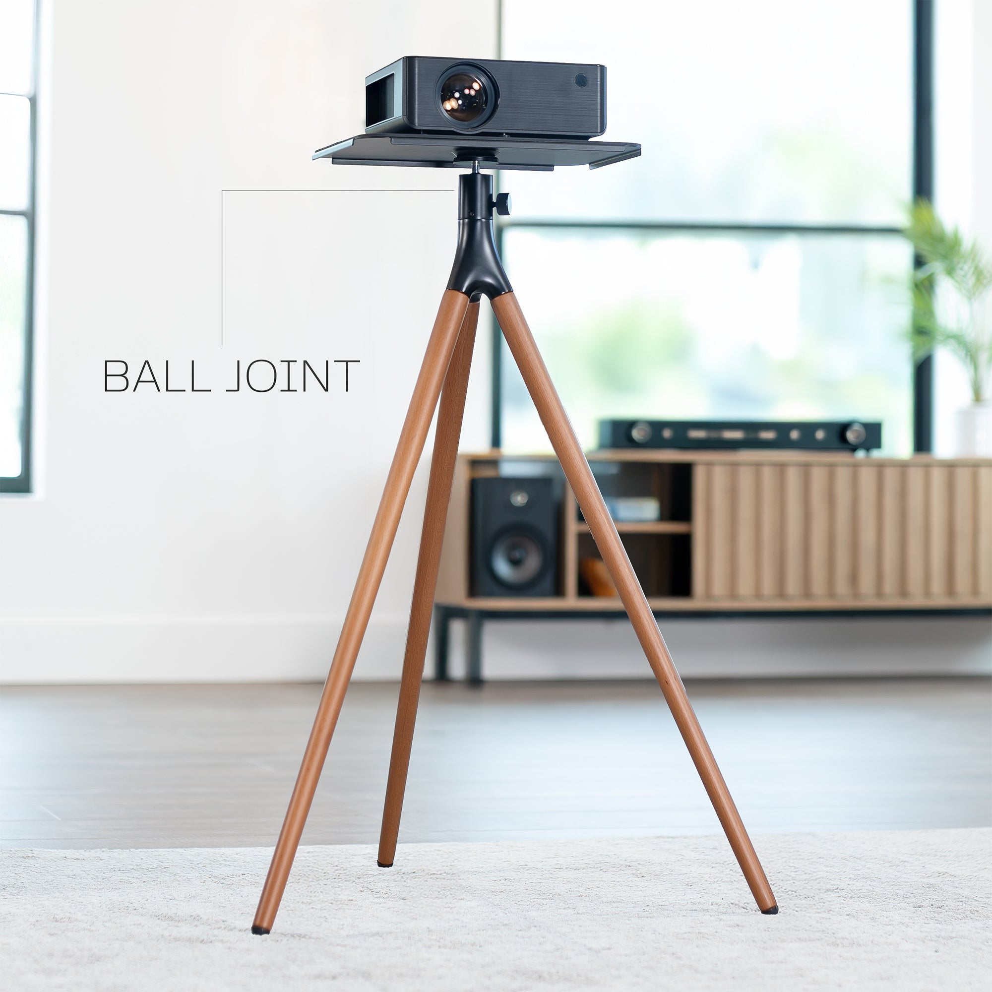 Projector on a wooden tripod in a room with furniture and decor.