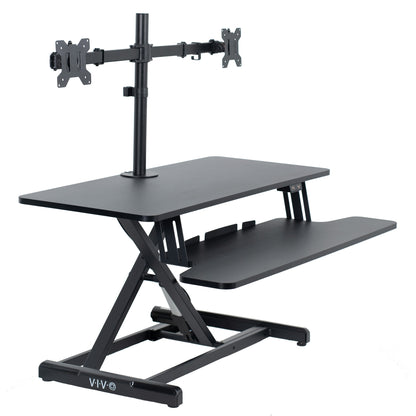 Sit to stand desk riser and dual monitor mount with electric height adjustment.