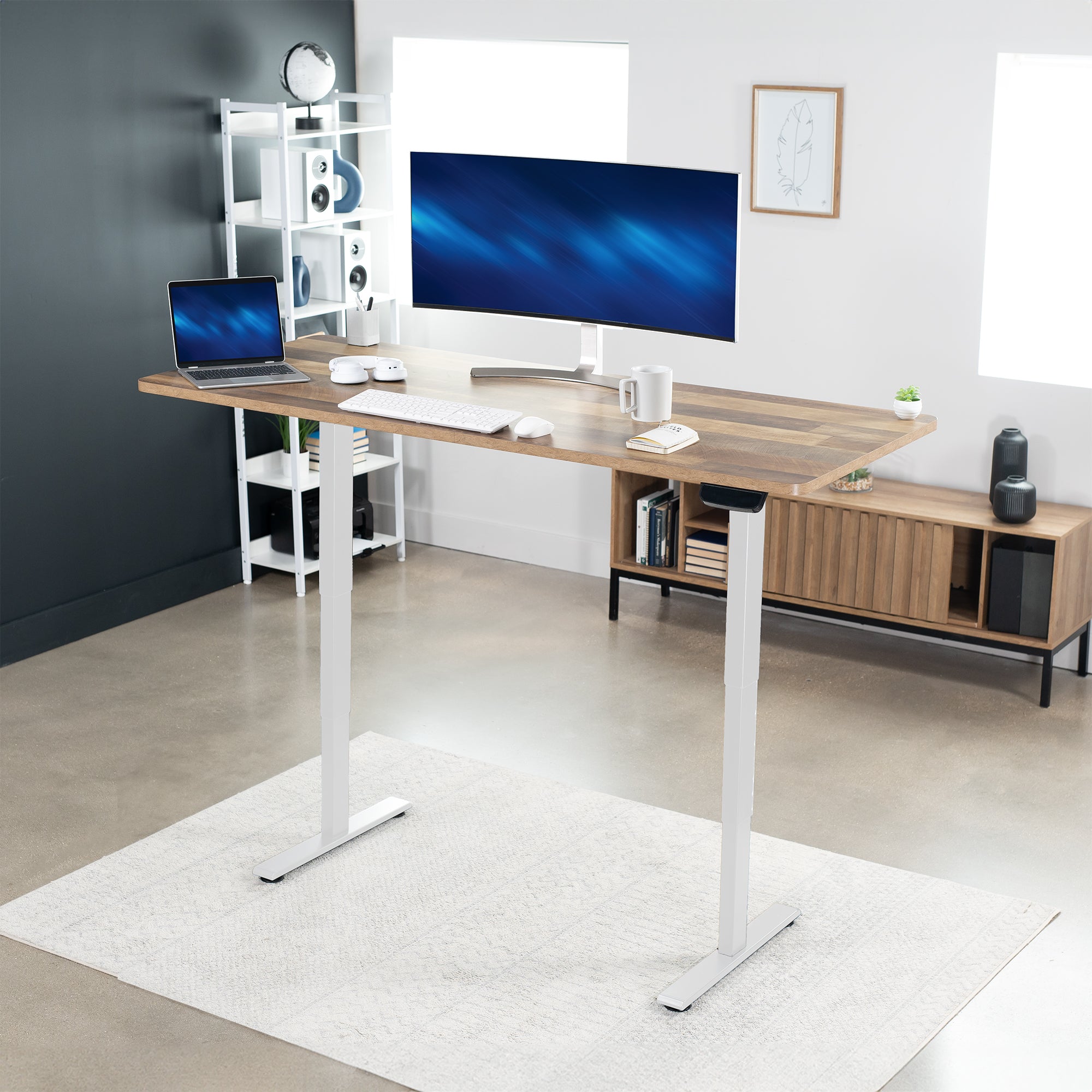 Modern home office with a adjustable height desk, computer setup, and shelves.