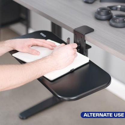 Single Clamp Rotating Keyboard Tray being used as an extension of the desk by a man writing in a notebook. 