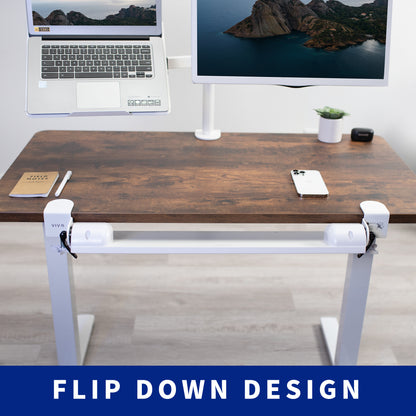 Wooden desk with a laptop, monitor, phone, and notebook on a light wood floor.