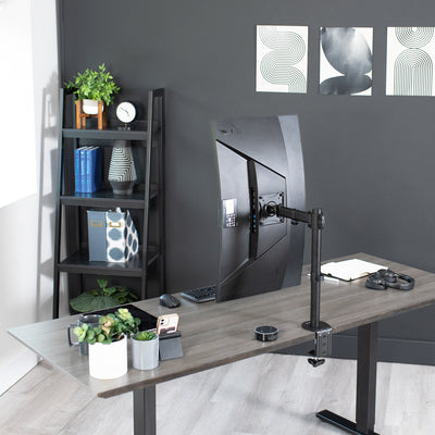 Modern office workspace set up with a monitor mount and sit-to-stand electric desk.