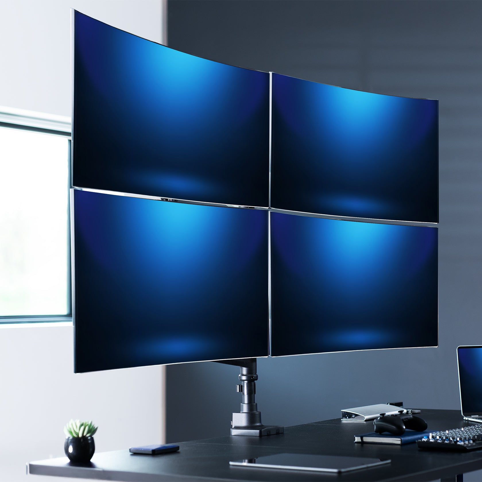 Pneumatic arm quad ultrawide monitor desk mount in an office area.