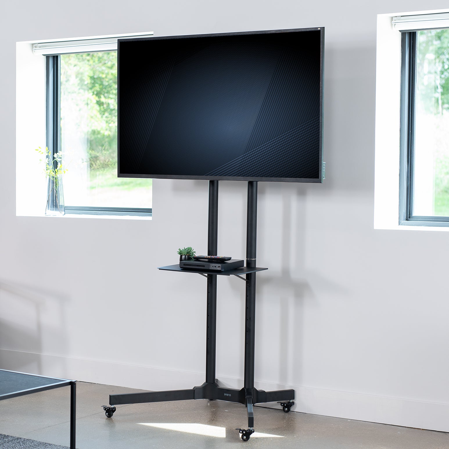 Mobile TV cart displays large screen on rolling stand for ergonomic viewing.