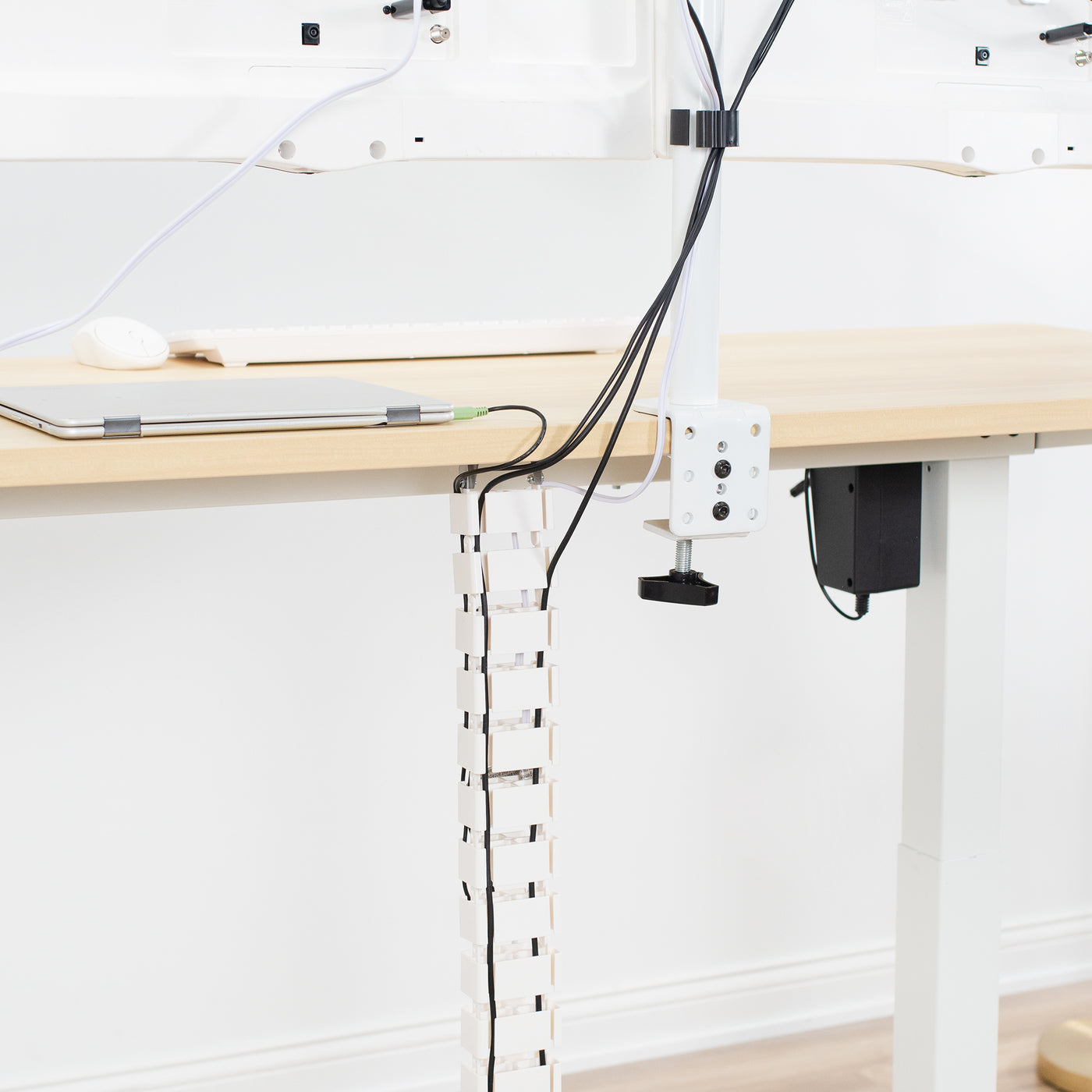 Vertebrae cable management attached vertically to white dual monitor C-clamp mount. 