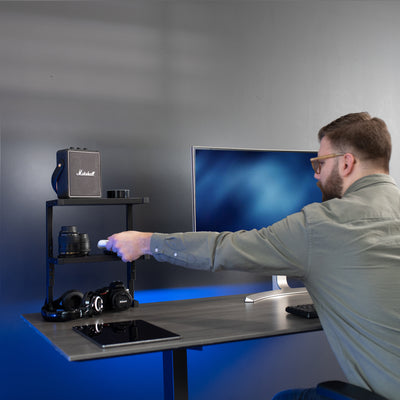 A man placing air pods on a dual clamp on a desk shelf.